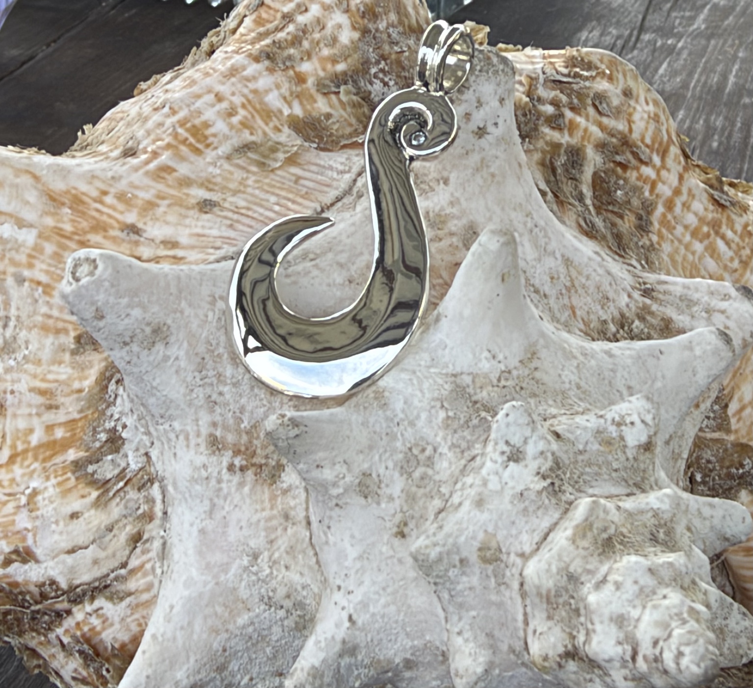 Handgemaakte vishaak hanger met spiraaldetail op een schelp